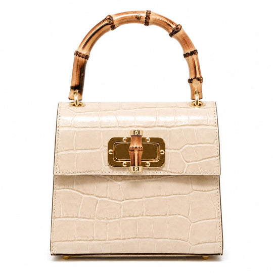 Cream-colored mini leather bag with a crocodile texture, gold hardware, and a distinctive arched bamboo handle.