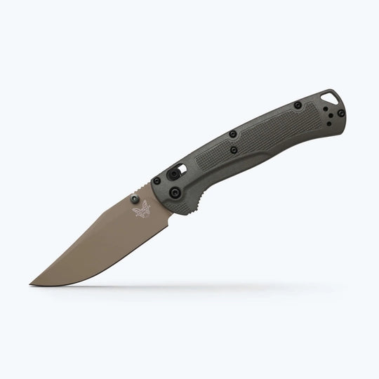 Benchmade Taggedout folding knife with a tan clip-point blade and textured olive green handle on a white background.