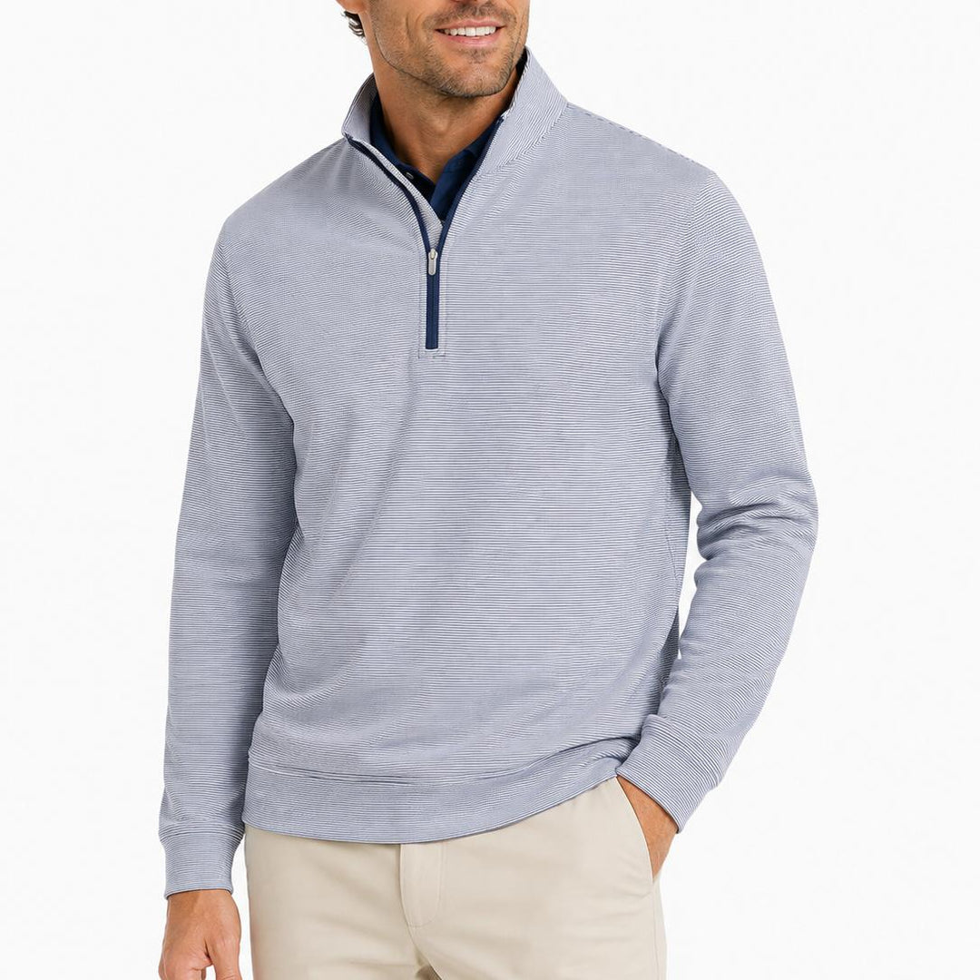 Man wearing a blue and white sugar stripe Peter Millar Perth performance quarter-zip pullover with a mock collar.