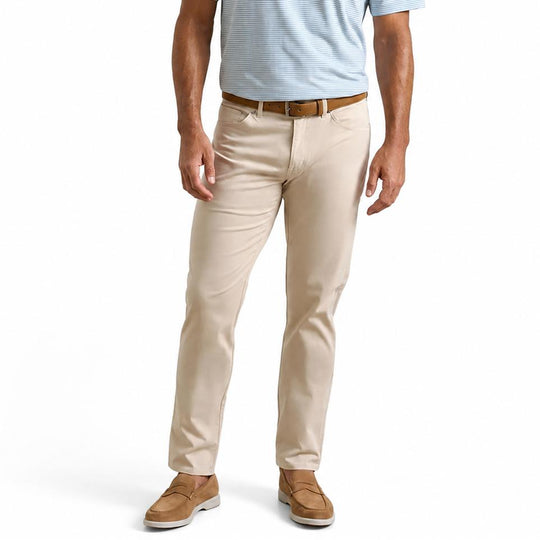Peter Millar beige sateen five-pocket pants with a comfort waistband and classic fit, paired with a brown leather belt.