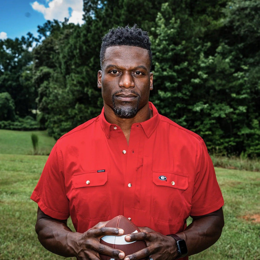 Man wearing a red University of Georgia performance shirt with magnetic chest pockets and a UGA logo outdoors.