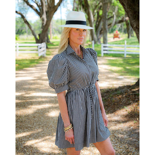 Woman wearing a checkered dress and hat in a park-like setting