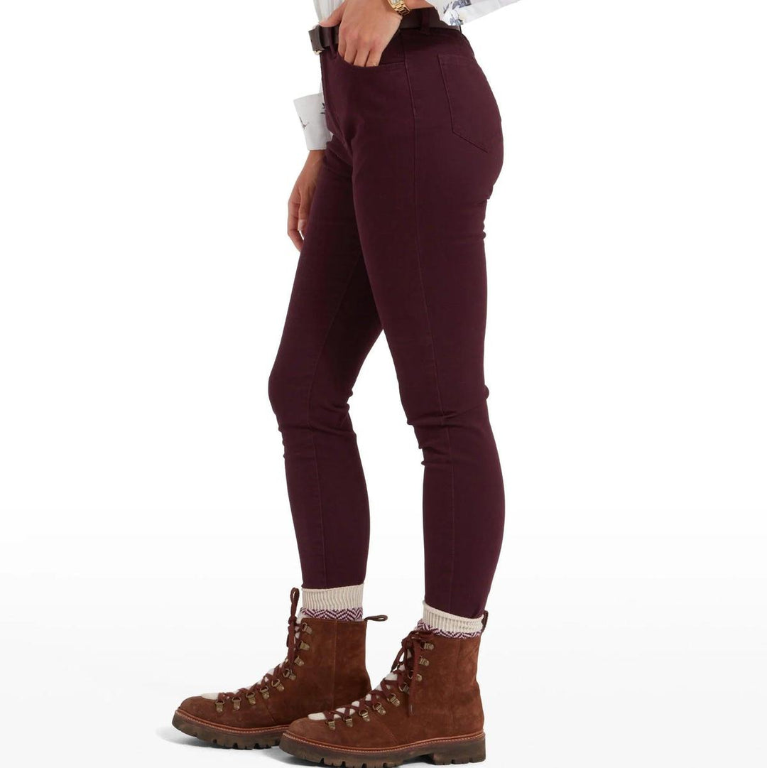 Side profile of Schoffel Poppy slim-fit high-rise jeans in deep plum, paired with brown suede hiking boots.
