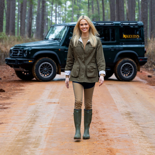 Woman wearing Kevin's Huntress jeans with waxed briar-facing panels, paired with olive green boots on a dirt road.