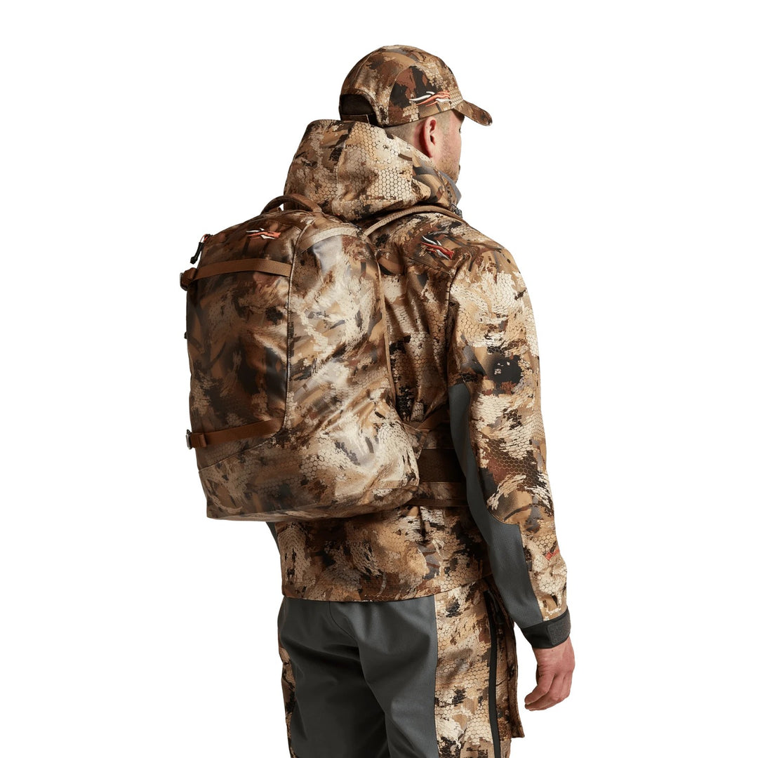 Hunter wearing a Sitka Full Choke Pack in camouflage, featuring a waterproof RF-welded design and durable TPU-coated fabric.