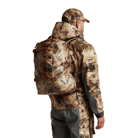 Hunter wearing a Sitka Full Choke Pack in camouflage, featuring a waterproof RF-welded design and durable TPU-coated fabric.