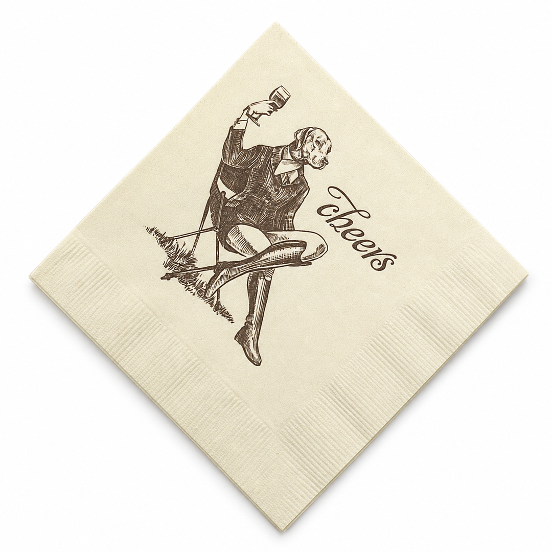 Cream-colored 5-inch 3-ply paper cocktail napkin featuring a whimsical illustration of a dog in a suit with the word cheers.