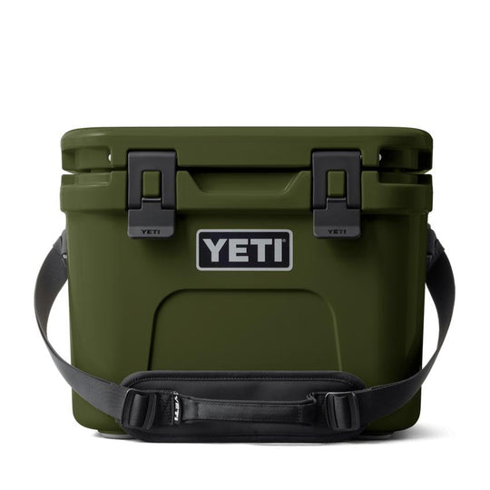 Olive green YETI Roadie 15 hard cooler with a black carrying strap, secure latches, and a front brand logo.