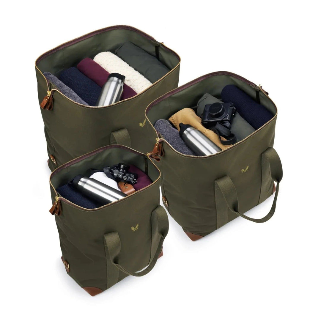 Three olive green Bennett Winch cargo bags in different sizes, featuring waterproof nylon, leather trim, and brass hardware.