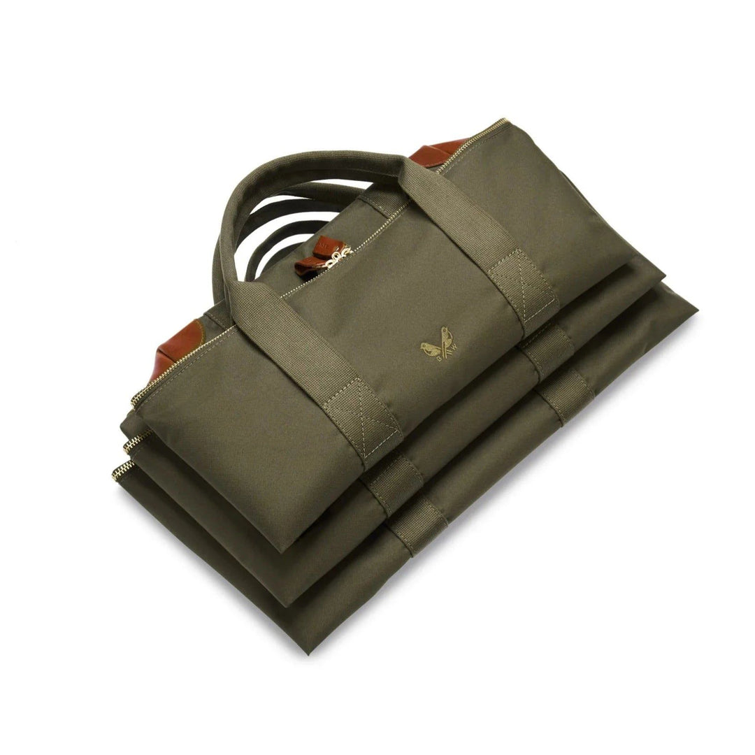 Olive green Bennett Winch cargo bag folded flat, featuring durable nylon, brown leather trim, and solid brass hardware.