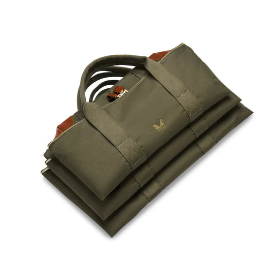 Olive green Bennett Winch cargo bag folded flat, featuring durable nylon, brown leather trim, and solid brass hardware.