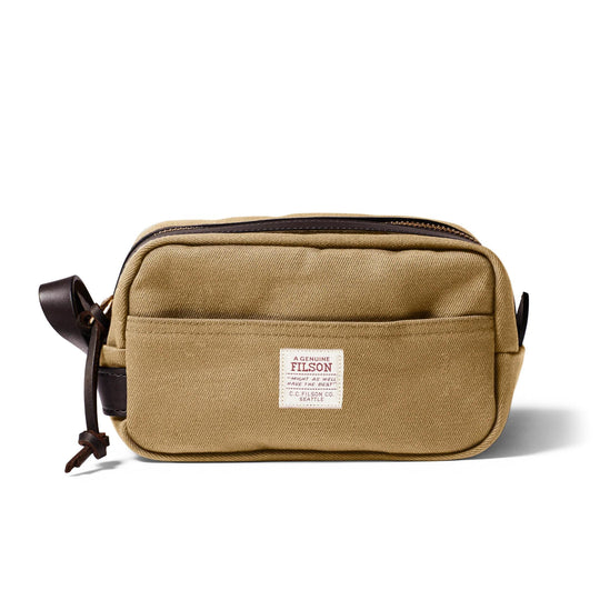 Tan rugged twill travel kit with brown bridle leather accents, side carry handle, and brass zipper closure.