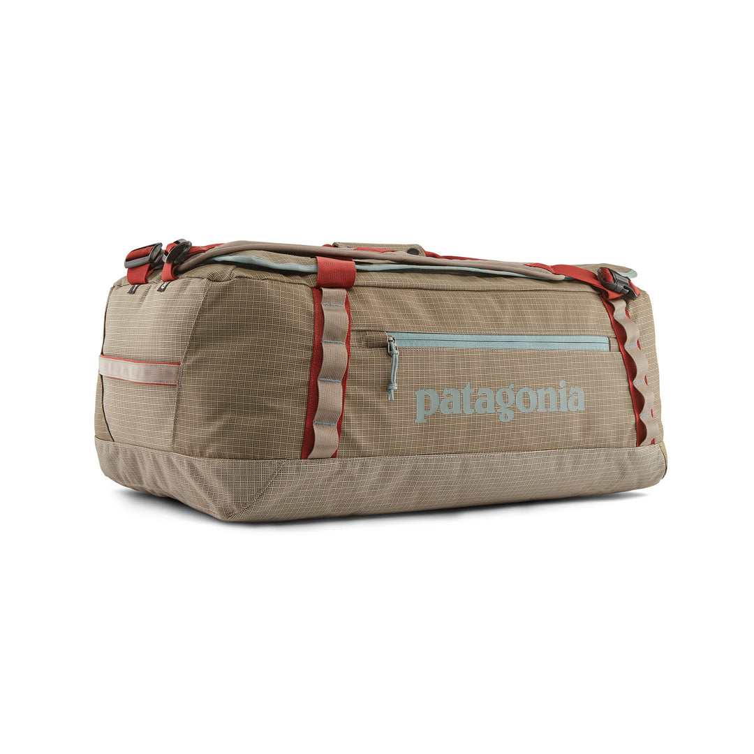 Tan Patagonia Black Hole 55L duffel bag in durable ripstop fabric with red straps, daisy chains, and a side zipper pocket.