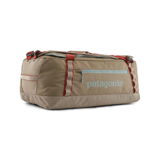 Tan Patagonia Black Hole 55L duffel bag in durable ripstop fabric with red straps, daisy chains, and a side zipper pocket.