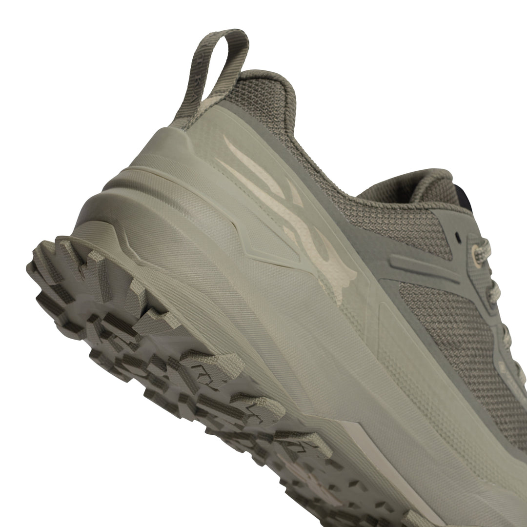 A close-up of a gray trail running shoe showing the side profile, textured midsole, and rugged outsole against a white background.
