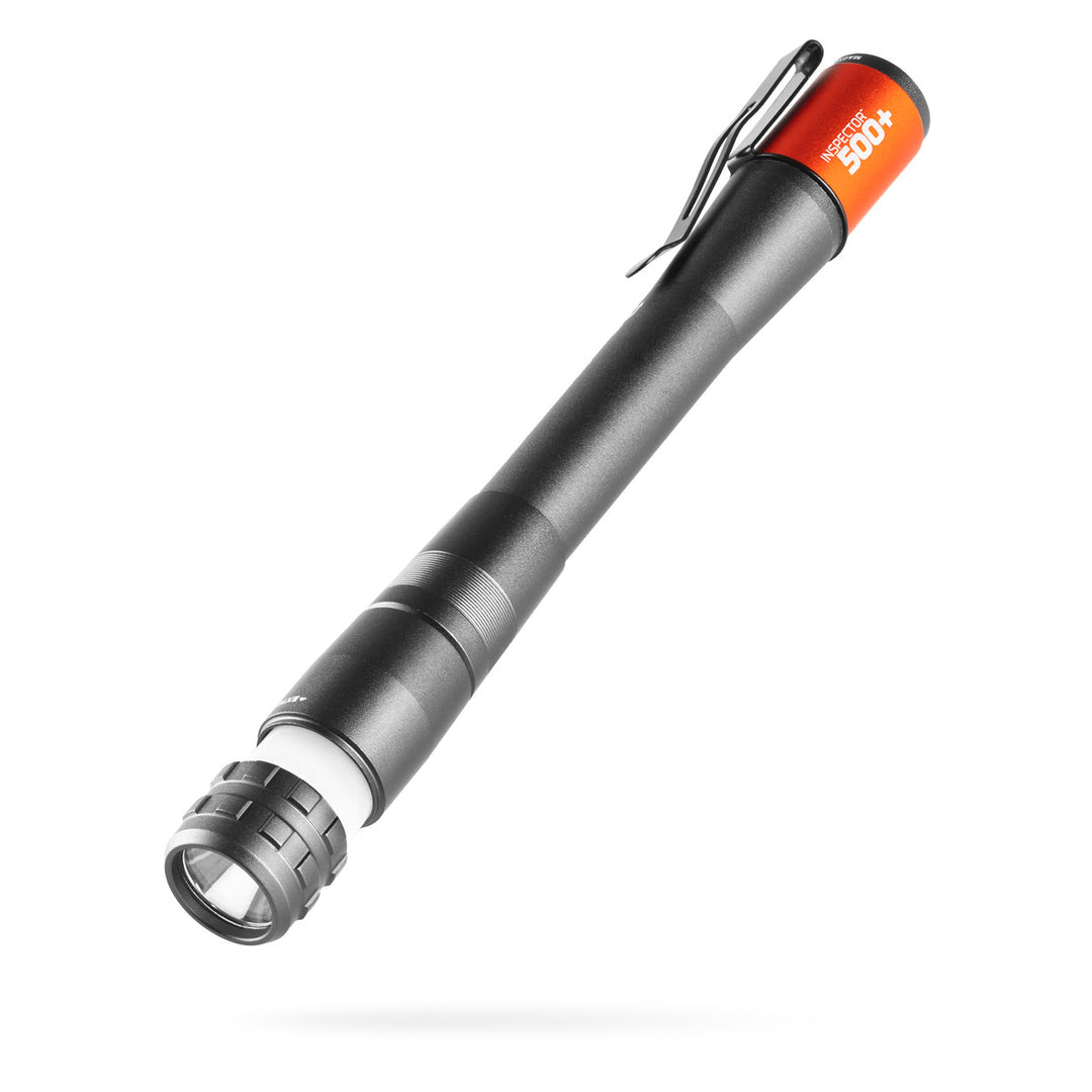 Black NEBO Inspector 500+ penlight with an orange end cap, metal pocket clip, and partially extended white area light.