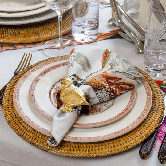 Cotton-canvas game bird napkin with Kat McCall artwork, held by a gold bird napkin ring on a formal place setting.
