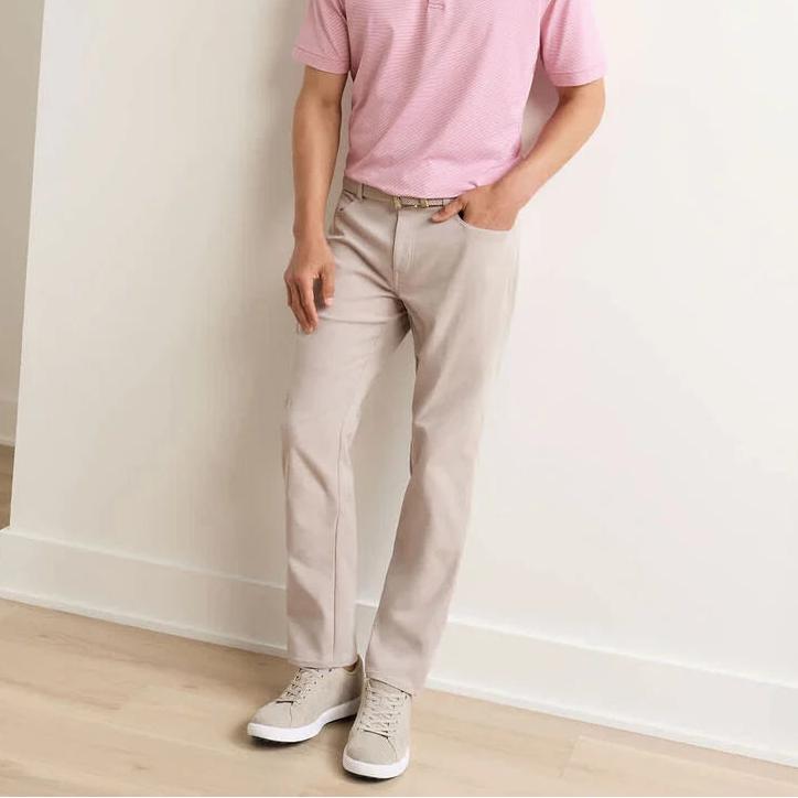 Man wearing beige Peter Millar EB66 performance five-pocket pants in stretch twill fabric with a comfortable waistband.
