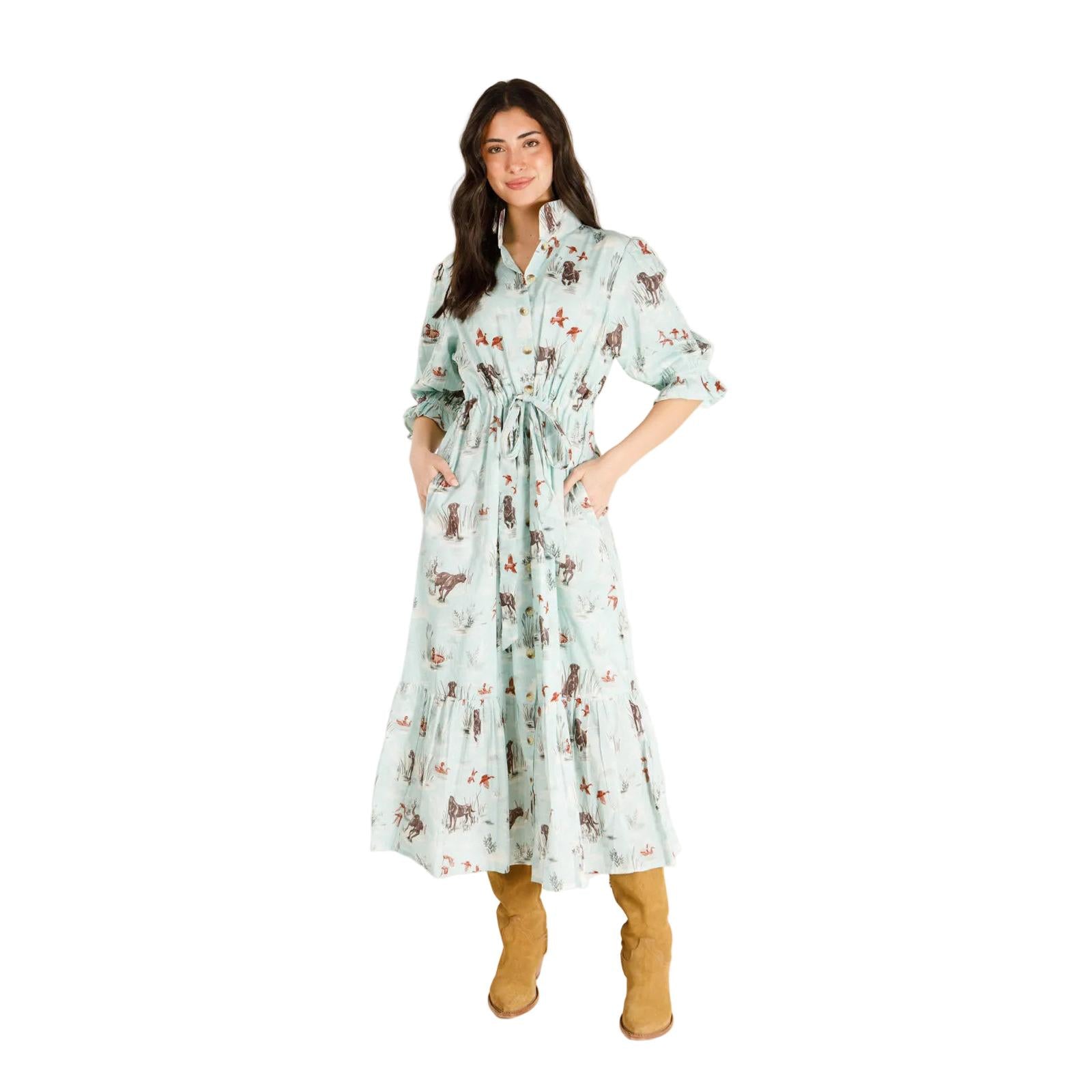 Model wearing a light blue midi shirt dress with a hunting-themed print, featuring a cinched waist and tiered skirt.