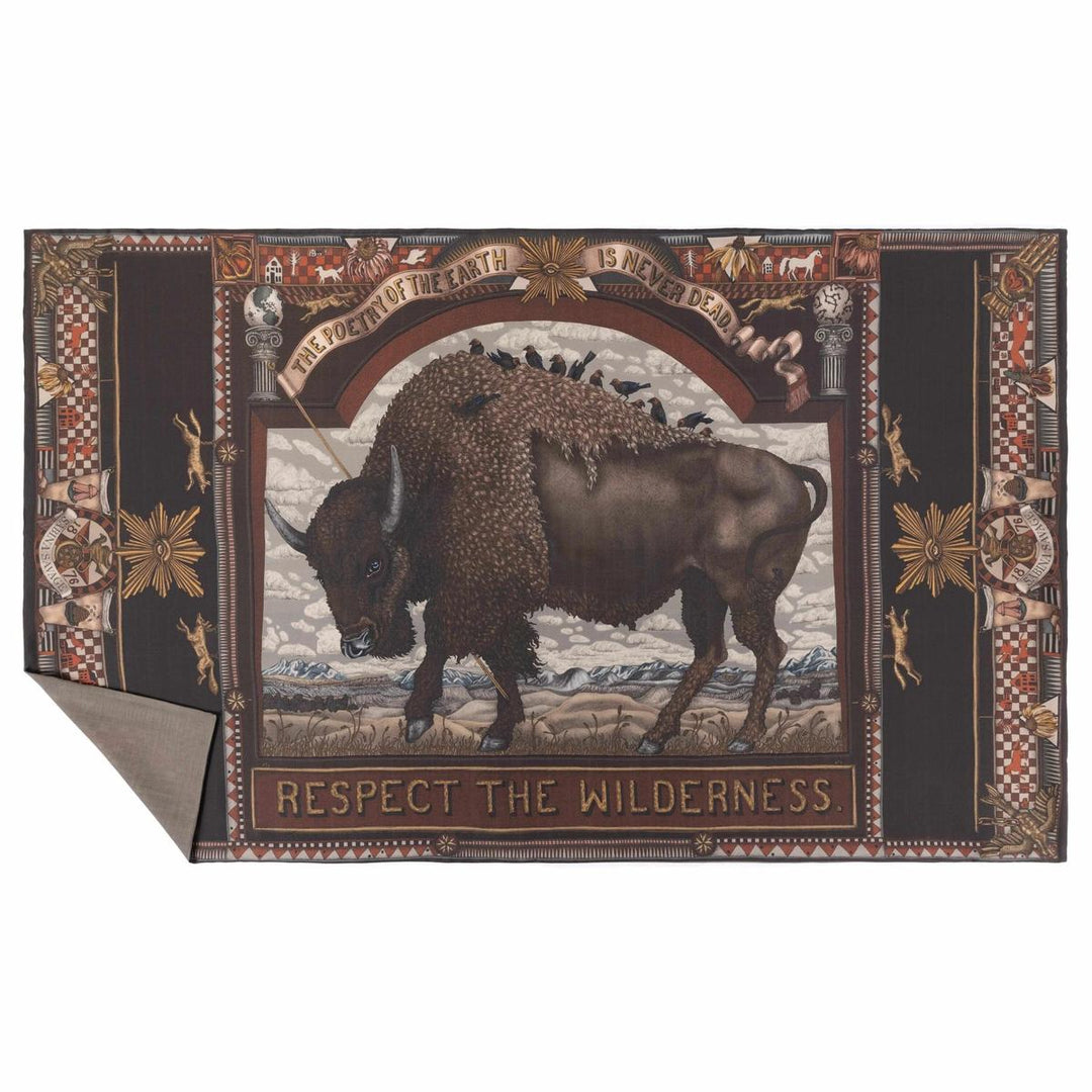 Brown cashmere stole featuring a central bison illustration, folk art motifs, and text on a dark, ornate decorative border.