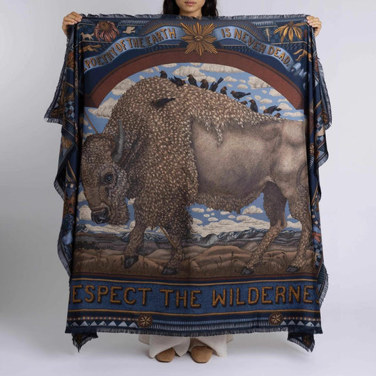 Sabina Savage silk rectangle scarf featuring a detailed bison illustration, folk art motifs, and blue borders with fringe.