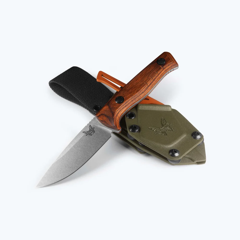A fixed-blade knife with a silver steel blade, a reddish-brown wood handle, and a black nylon sheath, displayed crossed over an olive green nylon sheath on a clean white background.
