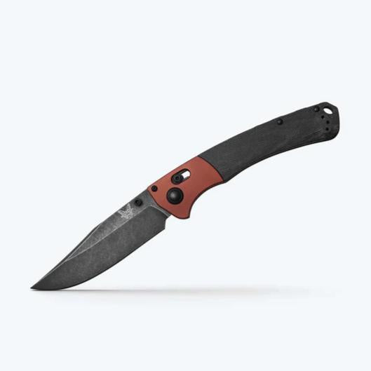 Folding knife with a black blade and red handle on a white background