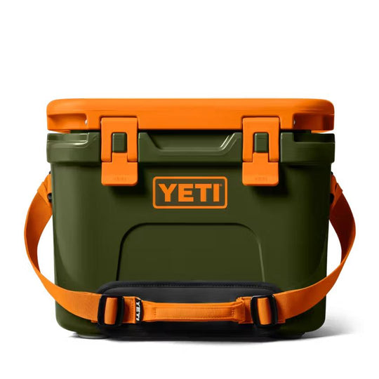 Olive green YETI Roadie 15 hard cooler with bright orange lid, latches, and adjustable carrying strap.