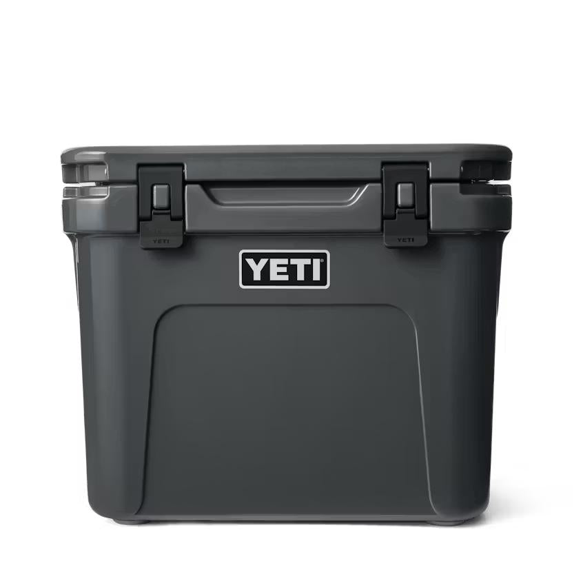 Charcoal grey YETI Roadie 32 wheeled cooler with a durable, rugged design and secure latch closures.