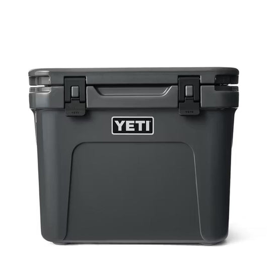 Charcoal grey YETI Roadie 32 wheeled cooler with a durable, rugged design and secure latch closures.