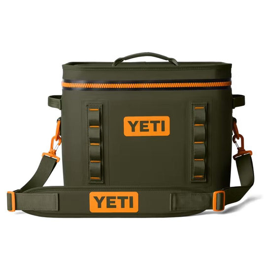 Olive green YETI Hopper Flip 18 soft cooler with orange accents, shoulder strap, and front HitchPoint grid on white.